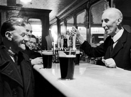 Landlord James Downeyserving a pint to one of his regulars. 16th February 1948
