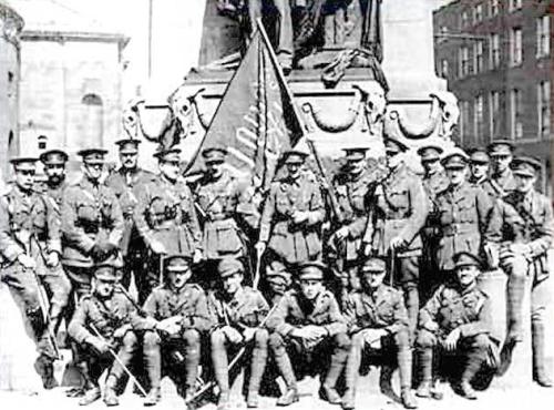 Members of the British forces pose with the captured 'Irish Republic' flag at the Parnell statue.